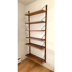 an empty room with wooden shelves and hard wood flooring on the side, in front of a white wall