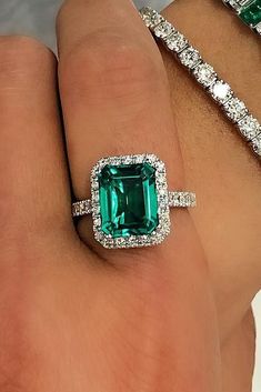 a woman's hand with two emeralds and diamond bracelets on her wrist