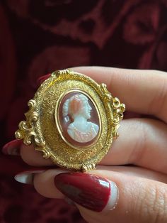 An adornment worthy of a museum! This stunning 19th century Sardonyx Cameo is a testament to Napoleon era French jewelry design. Crafted circa 1850-1860 in 18 carat gold, this brooch features a vibrant cameo of a aristocratic woman, set again a delicate peachy-hued sardonyx mount. The 18-carat gold mounting is also exceptional, with a gilded design brimming with fine detailing, and scrolling foliate motifs. The silhouette it creates makes it feel as if it should be hung in the halls of a palace! Antique Yellow Gold Brooches With Intricate Design, Yellow Gold Baroque Brooch For Formal Occasions, Antique Gold Jewelry For Opera, Formal Yellow Gold Baroque Brooches, Vintage Yellow Gold Baroque Brooch, Victorian Oval Jewelry For Opera, Victorian Hallmarked Jewelry For Opera, Luxury Gold Brooches With Intricate Design, Victorian Gold Brooch With Intricate Design