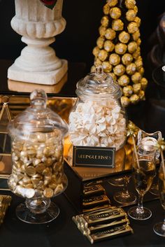 a table topped with lots of chocolate covered candies next to a glass vase filled with candy