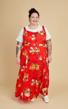 a woman wearing a red floral dress and white t - shirt smiles at the camera