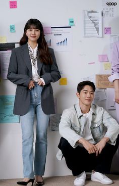 a woman standing next to a man in front of a whiteboard with sticky notes on it