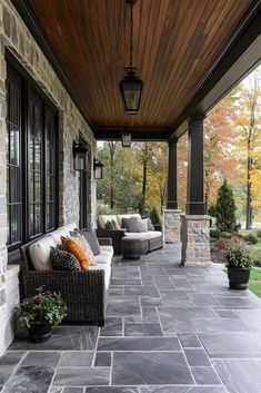 a covered porch with couches and potted plants on the side walk next to it