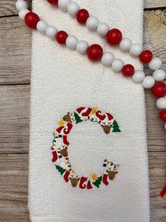 a white towel with a red and white beaded christmas wreath hanging from it's side