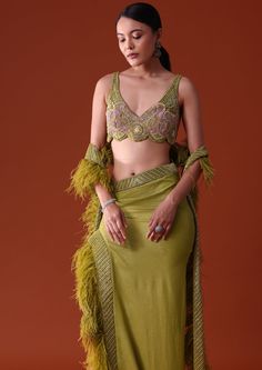 Revealing an ensemble that combines elegance with unparalleled innovation is this citrus green ensemble. Featuring a feathered dupatta embellished blouse and dhoti skirt that redefines contemporary fashion with a blend of vibrant aesthetics and sophisticated details. Styled in a refreshing citrus green the sleeveless blouse grabs attention with its v neckline creating a sleek silhouette that highlights the décolletage. Dry clean only if required. Slight variation in color is possible due to digital photography. Pista Green Embellished Pre-draped Saree For Diwali, Pista Green Embellished Saree For Diwali, Embellished Pista Green Pre-draped Saree For Diwali, Diwali Embellished Pista Green Pre-draped Saree, Green Hand Embellished Sets In Traditional Drape, Green Hand Embellished Sets With Traditional Drape, Green Hand Embellished Dupatta, Glamorous Green Lehenga, Green Hand Embellished Sets For Designer Wear