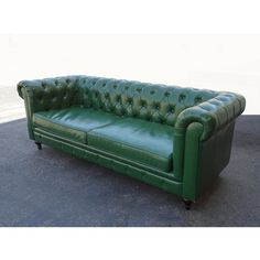 a green leather couch sitting on top of a cement floor