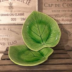 a green leaf shaped bowl sitting on top of a wooden table