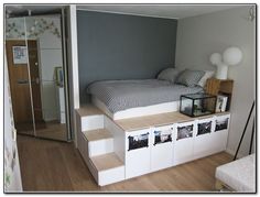 a bedroom with stairs leading up to the bed and storage space under it, in front of a door