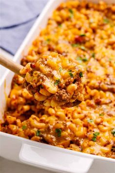 a spoon full of macaroni and cheese being lifted from a casserole dish