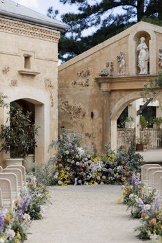 an outdoor ceremony with chairs and flowers in the foreground, surrounded by archways