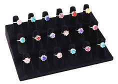 six pairs of rings are on display in a velvet ring holder with black velvet backing