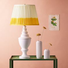 two vases and a lamp on a table in front of a wall with pink walls