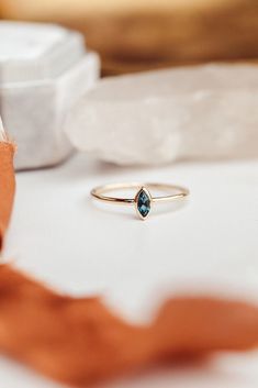 a blue diamond ring sitting on top of a white table next to some orange ribbon