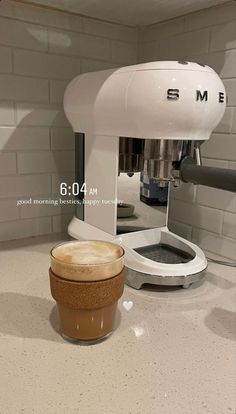 an espresso machine sitting on top of a counter next to a brown cup