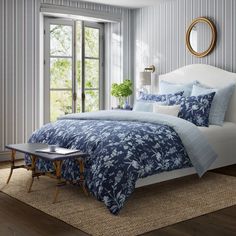 a bed with blue and white comforter in a bedroom next to a window,