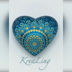 a blue and yellow heart shaped object with gold dots on it's sides, in front of a white background