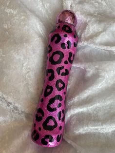 a pink and black leopard print bottle laying on top of a bed