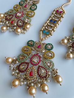 These gorgeous sets of tikka and jhumka come in 2 beautiful colors and are pastel tones to match any outfit. The multi set is a subtle mix of colors to create a uniform look and the champagne is the perfect single pop of color for any outfit! Comes as a set of earrings and headpiece (tikka) Elegant Multicolor Kundan Chandbalis, Elegant Multicolor Jhumkas For Parties, Elegant Multicolor Jhumkas For Festive Occasions, Elegant Multicolor Jhumkas For Celebration, Multicolor Bridal Earrings With Latkans, Multicolor Fusion Chandbalis For Celebrations, Elegant Multicolor Stone Work Chandbalis, Elegant Multicolor Chandbalis With Stone Work, Fusion Style Multicolor Chandbalis For Celebration