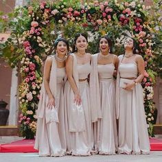 the bridesmaids are posing for a photo in front of an arch with flowers