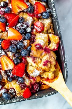 a casserole dish with berries and powdered sugar on top, ready to be eaten