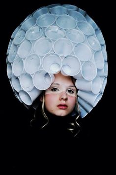 a woman wearing a large white hat made out of plastic cups on top of her head