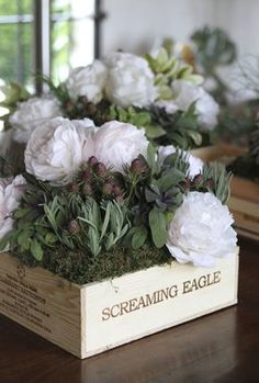 some white flowers are sitting in a wooden box on a table with the words screaming eagle painted on it