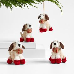 three stuffed dogs hanging from a christmas tree ornament, one in red and the other in white