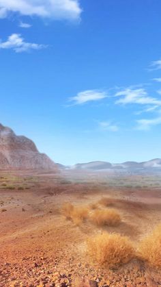 an arid landscape with mountains in the distance and blue sky above it, as seen from a moving vehicle