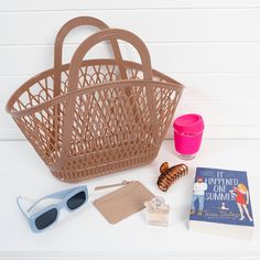 a basket, sunglasses, book and other items laid out on a white table top