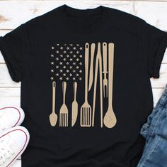 a t - shirt with utensils on it and an american flag in the background