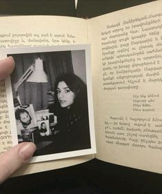 a person holding up an open book with black and white photos on the pages in front of them