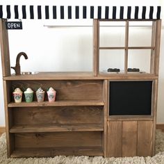 a wooden cabinet with three cups on top and a sign above it that says open