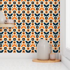 an orange and blue wallpaper with white vases on the counter next to it