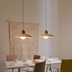 two pendant lights hanging over a dining room table