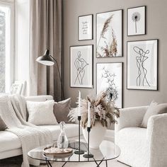 a living room filled with white furniture and pictures on the wall above it's coffee table