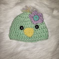 a crocheted green hat with flowers on the top and a button in the middle