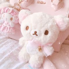 a white teddy bear sitting on top of a bed next to a pink handbag