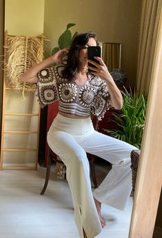 a woman is taking a selfie in the mirror while wearing white pants and a crop top