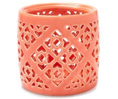 an orange candle holder is shown on a white background and has hearts cut out in the middle