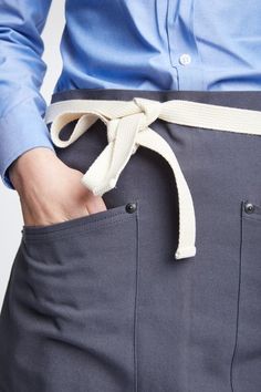 a man wearing a blue shirt and gray pants with a white belt around his waist