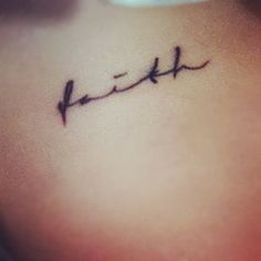 a small tattoo on the back of a woman's neck that reads, faith