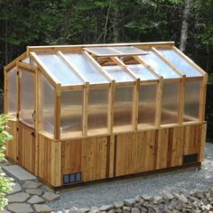 a small wooden structure with glass doors in the middle of some rocks and trees behind it