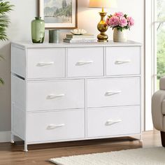 a white dresser with flowers and pictures on it