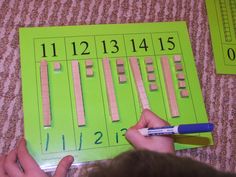 a child is writing numbers on a green piece of paper with crayon sticks