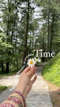 a person holding up a flower with the words time written on it in front of them