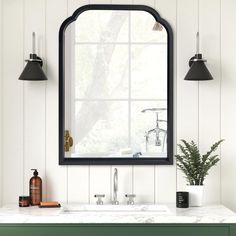 a bathroom sink under a large mirror next to a green cabinet and two black lights