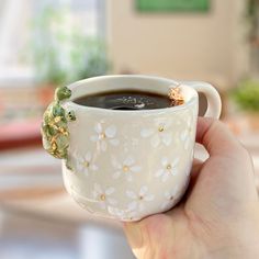 a person holding a coffee cup with a small turtle on it's handle and saucer in their hand