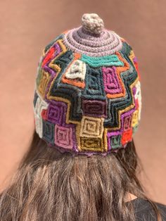 a woman with long hair wearing a multicolored knitted hat on top of her head