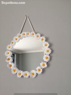 a mirror hanging on the wall with daisies in it