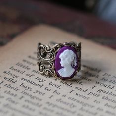 Oxidized sterling silver plated filigree ring which is adjustable.  In the center is a 14x10mm purple, blue, green, black or pink girl cameo. Antique Purple Rings As Gift, Antique Purple Rings For Gift, Purple Filigree Jewelry Gift, Vintage Adjustable Purple Jewelry, Adjustable Vintage Purple Jewelry, Purple Oval Filigree Jewelry, Vintage Adjustable Filigree Ring Gift, Purple Oval Filigree Ring For Gift, Purple Oval Filigree Ring As A Gift